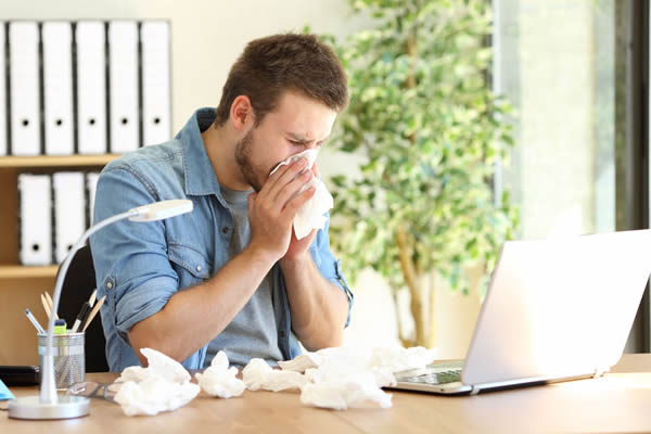 A man sneezing, suffering from allergies.