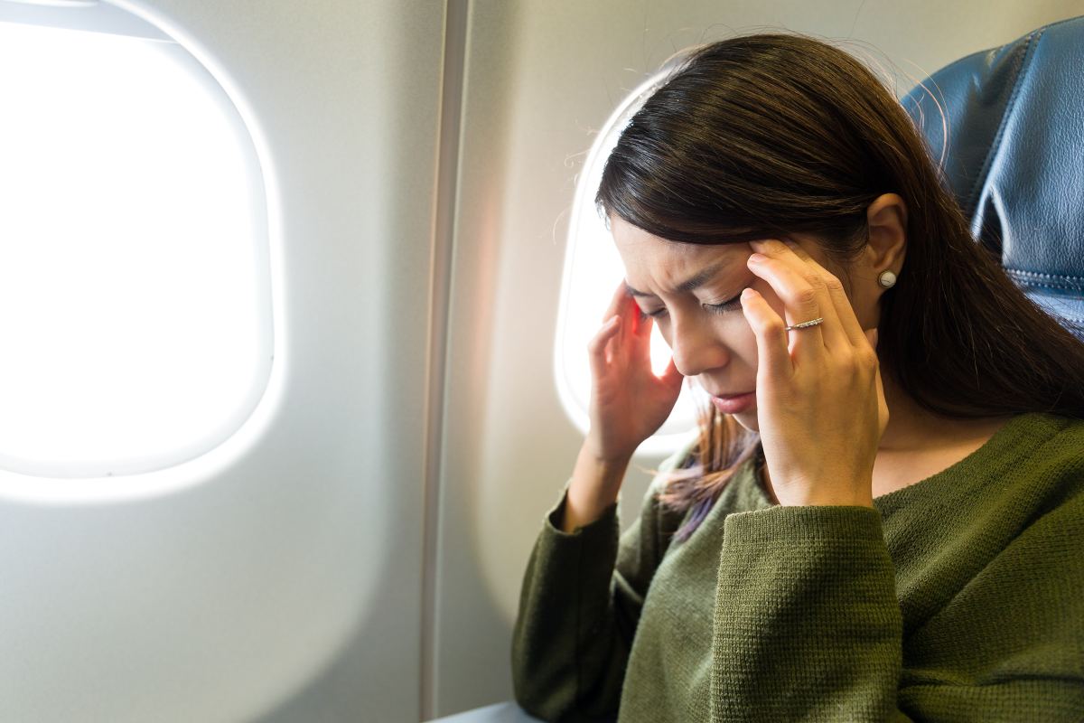 Woman experiencing sinus pain while on an airplane flight