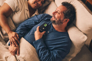Happy couple laying in bed with Inspire sleep apnea device